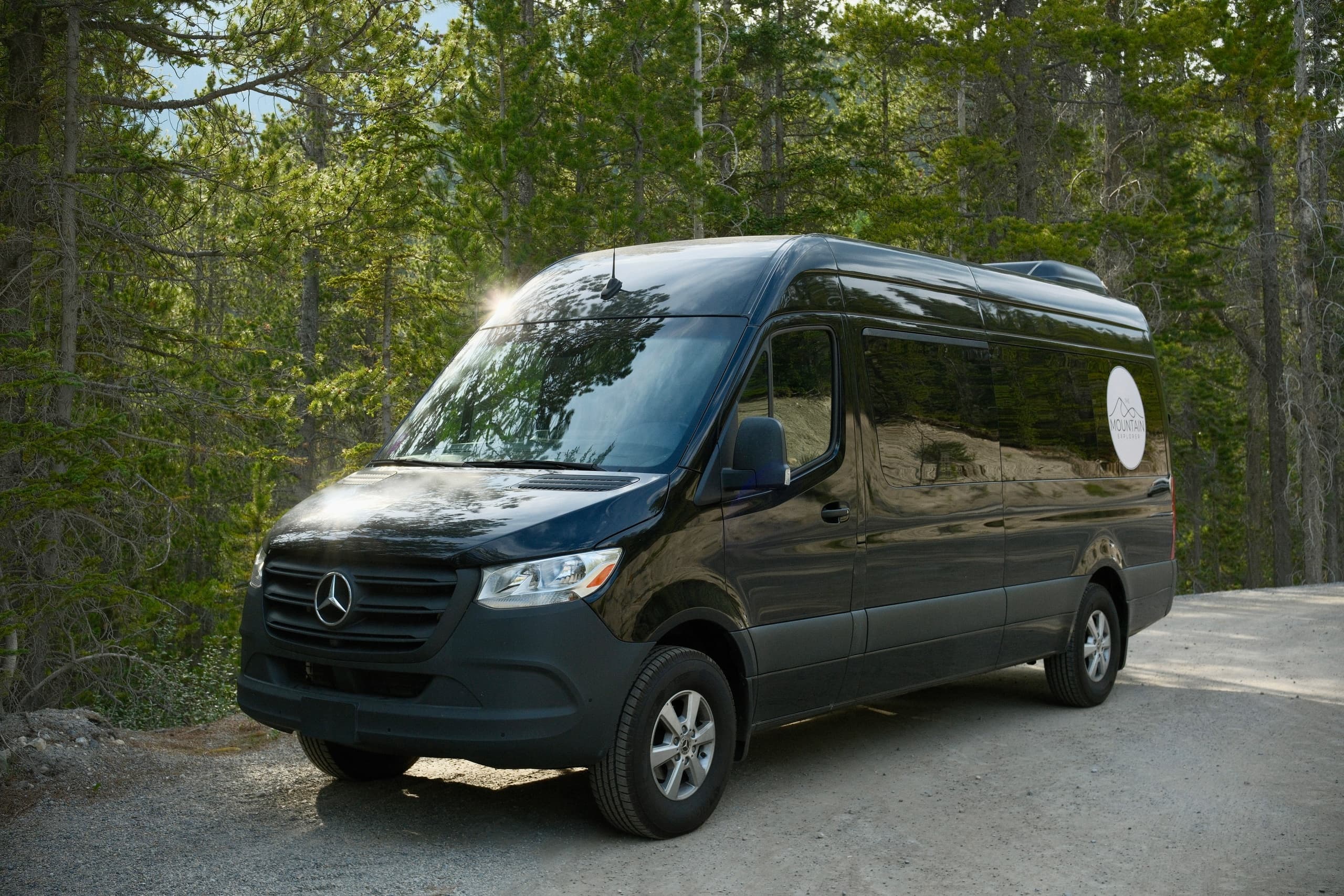 Shuttle van parked in forested trailhead, transportation to outdoor trips