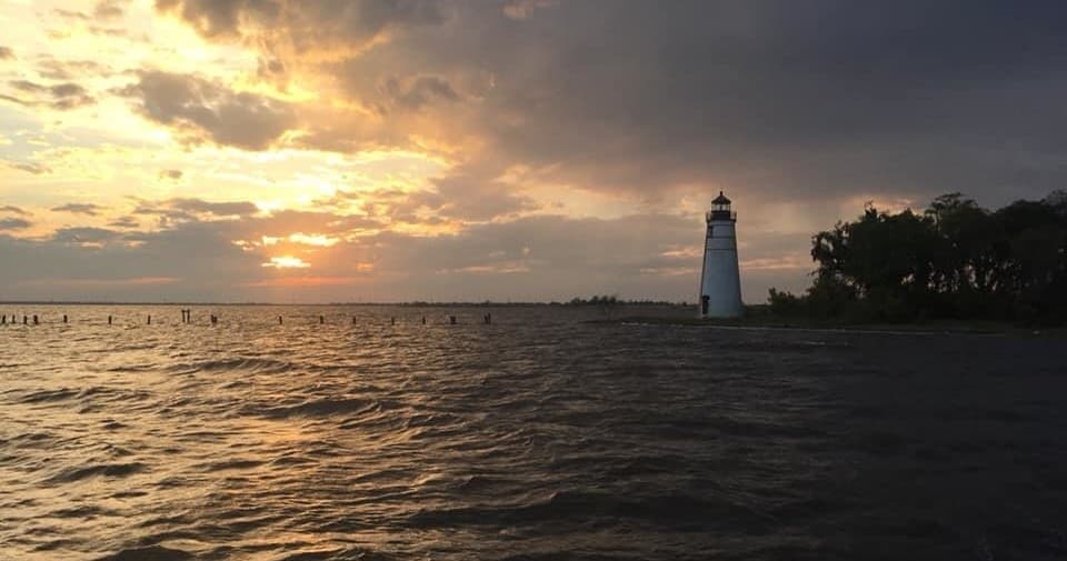 Lighthouse at sunset over coastal waters during boat tour