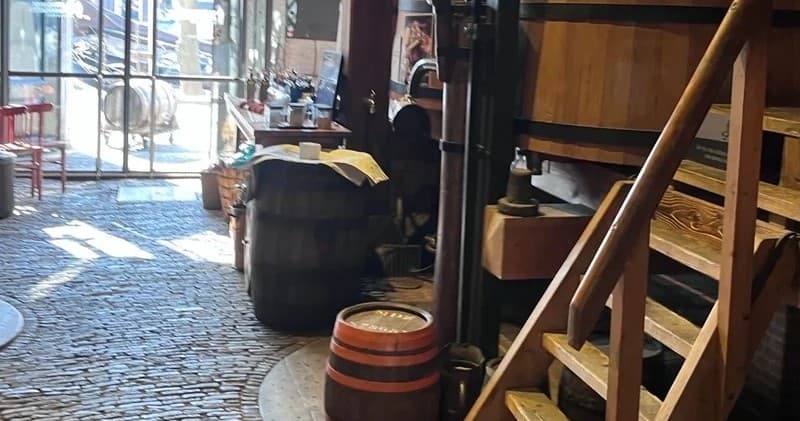 Rustic brewery tasting room interior with wooden barrels and stairs