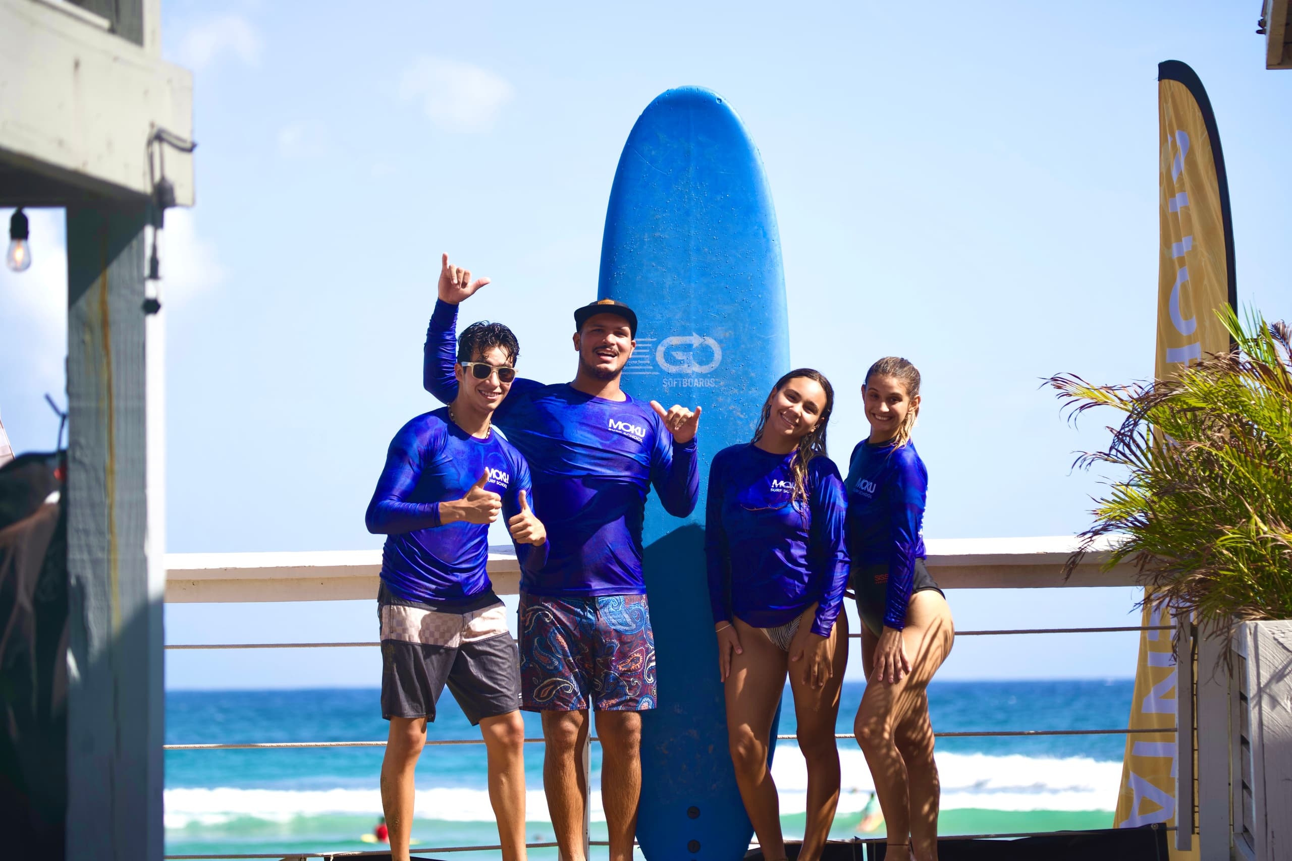 Surf instructors and students posing with board on Playa Jobos