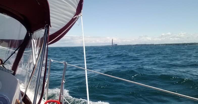 Sailboat underway on open blue lake waters under sunny sky
