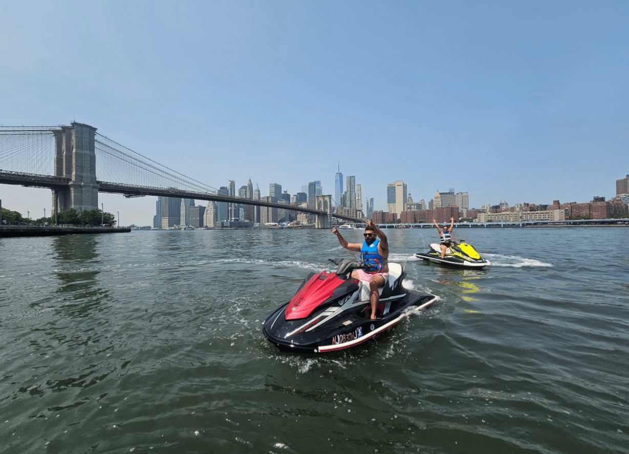 Jet skiers near Brooklyn Bridge and NYC skyline on clear day