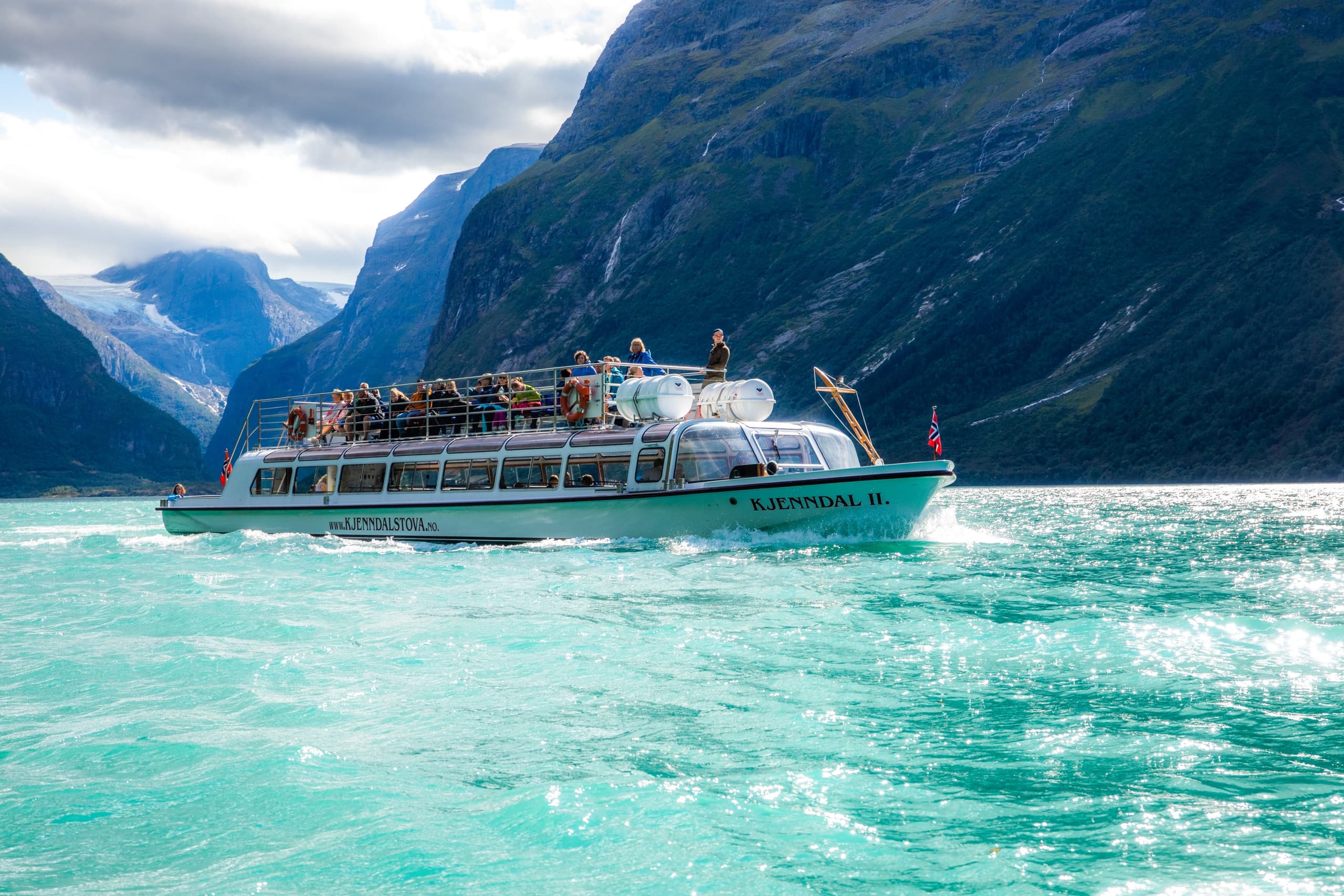 Sightseeing boat cruising turquoise fjord with mountain vistas