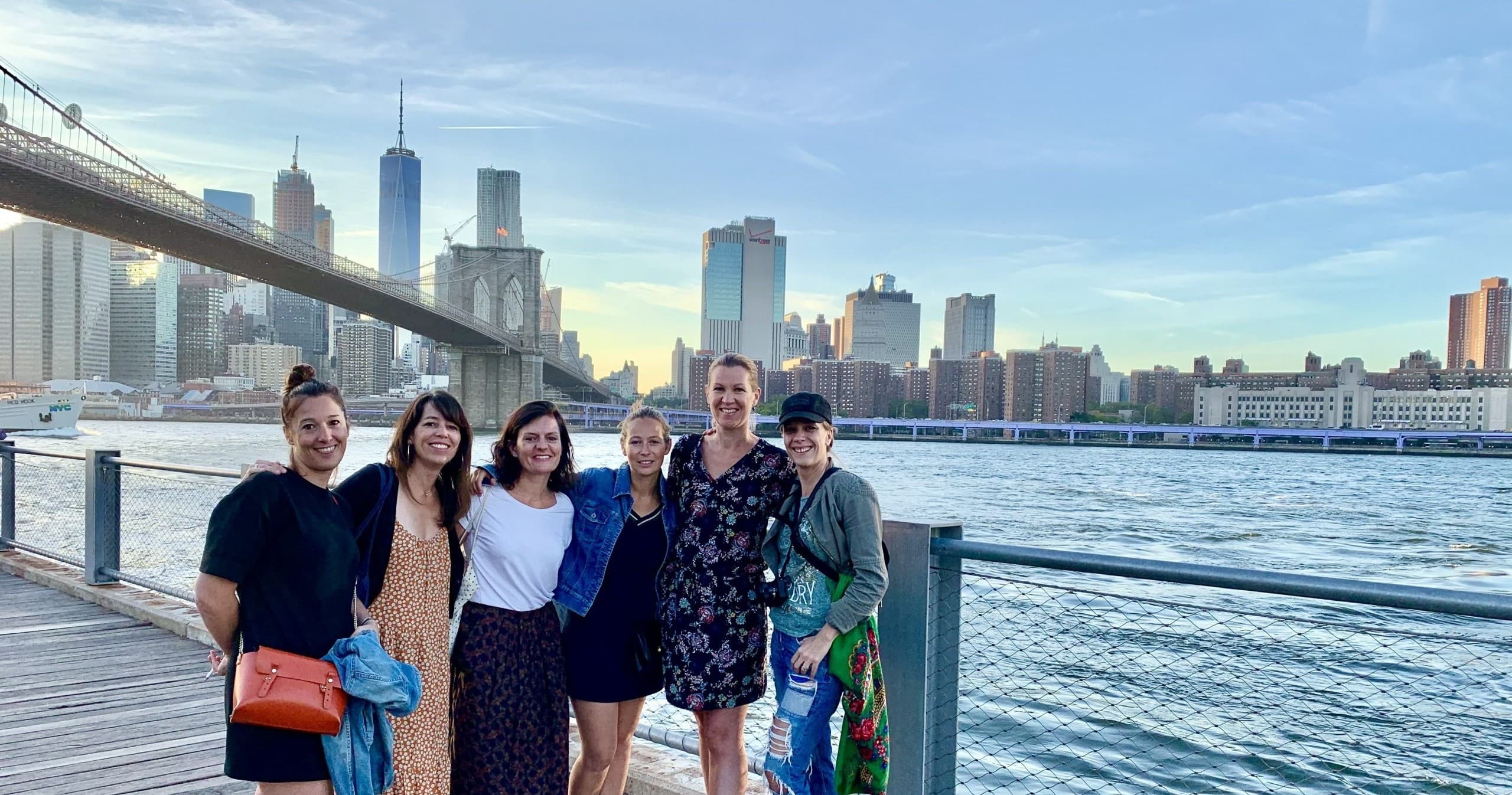 Friends standing on waterfront with Manhattan skyline sunset
