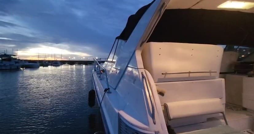 Docked motor yacht at marina during dusk, calm waters and lights