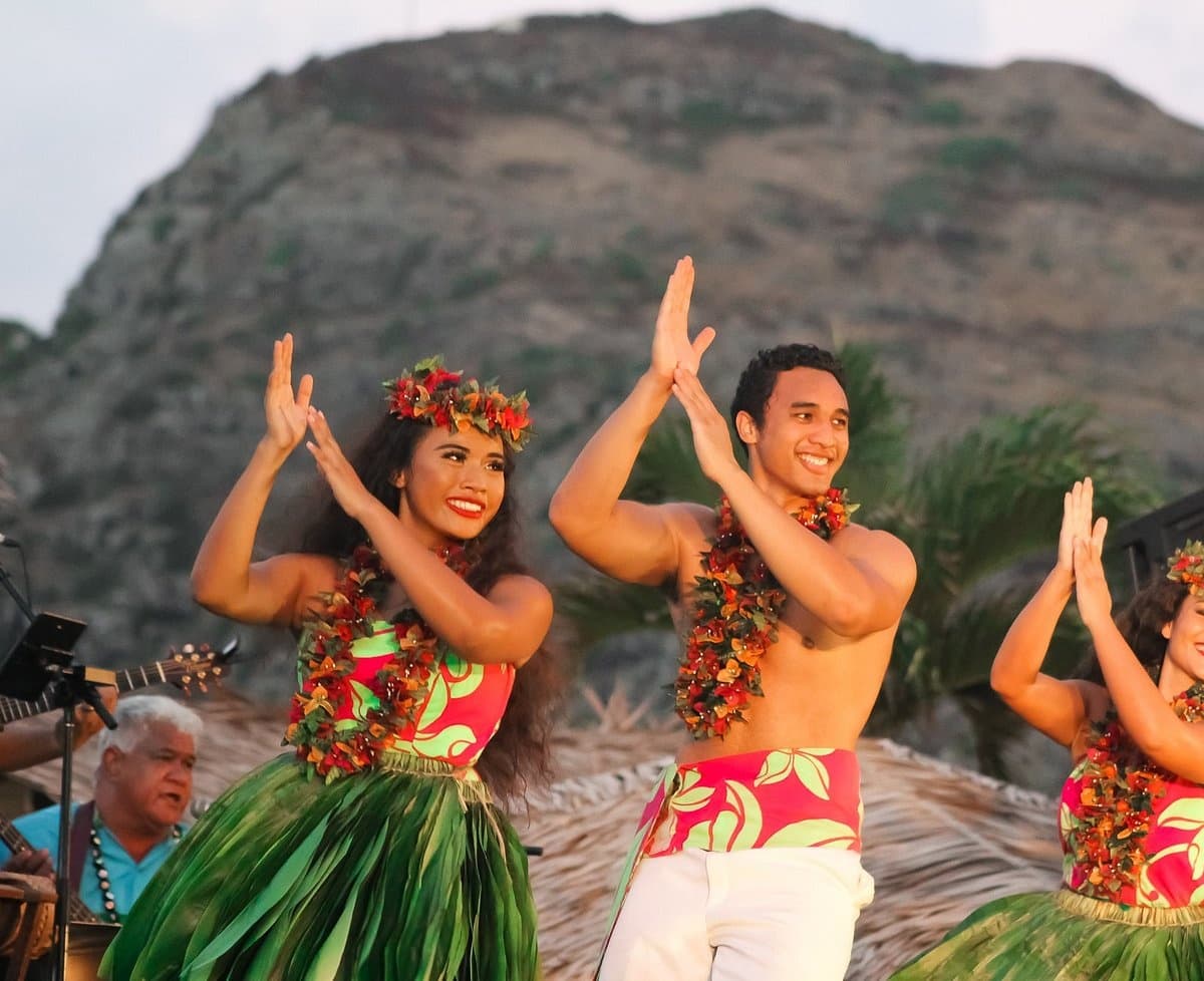 Hula dancers performing at sunset with volcanic ridge backdrop
