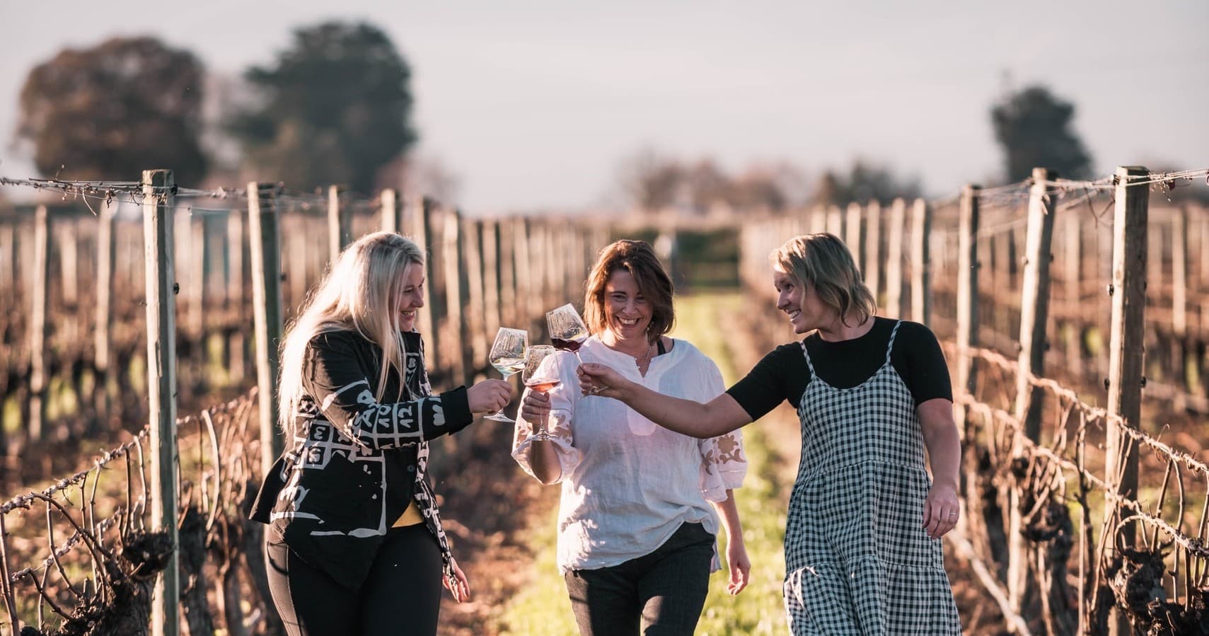 Friends walking vineyard rows tasting wine during Marlborough tour