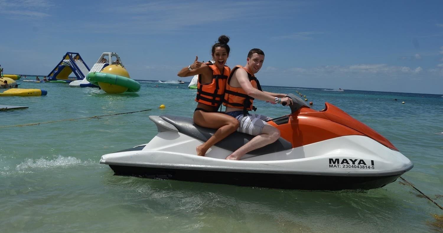 Couple riding jet ski on sunny Cozumel beach and shallow sea