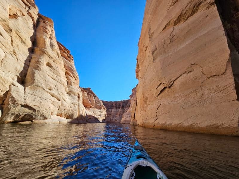 Kayak paddling through narrow sandstone canyon on calm river
