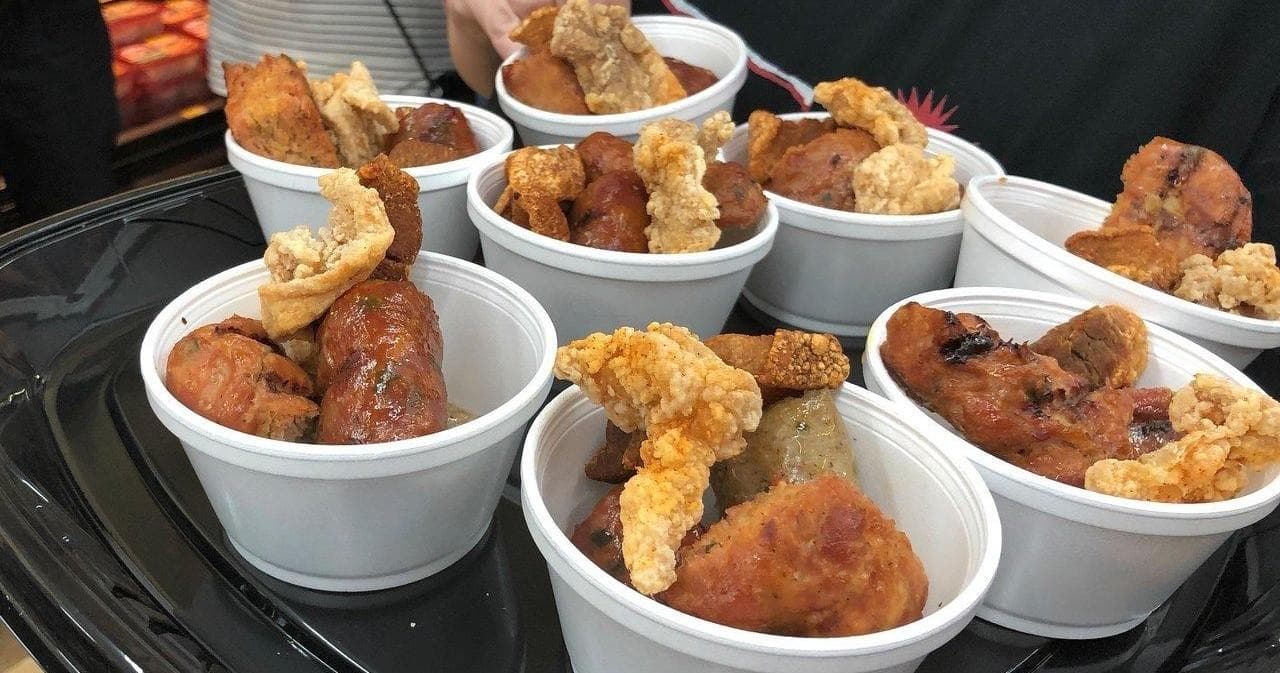 Sample cups of fried chicken and pork rinds at food tasting event