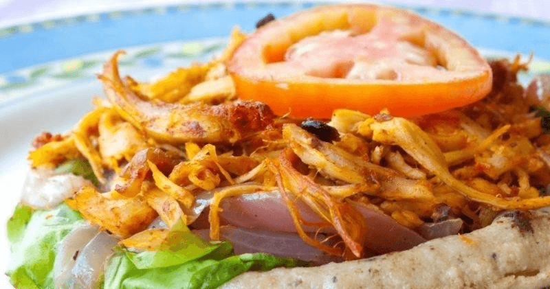 Close-up of loaded street sandwich with fried onions and tomato