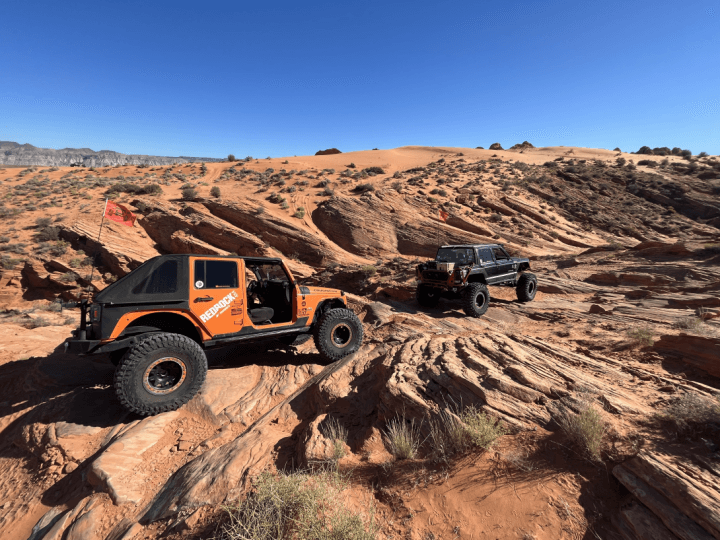 Off-road Jeeps climbing red sandstone slickrock in desert