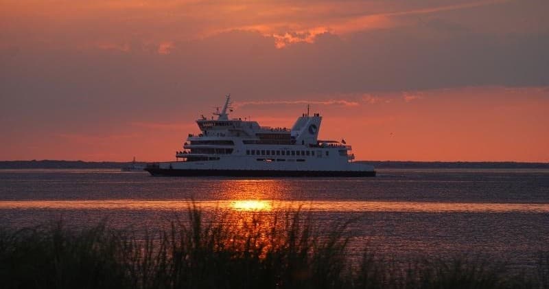 Passenger ferry cutting across bay at sunset, coastal voyage experience