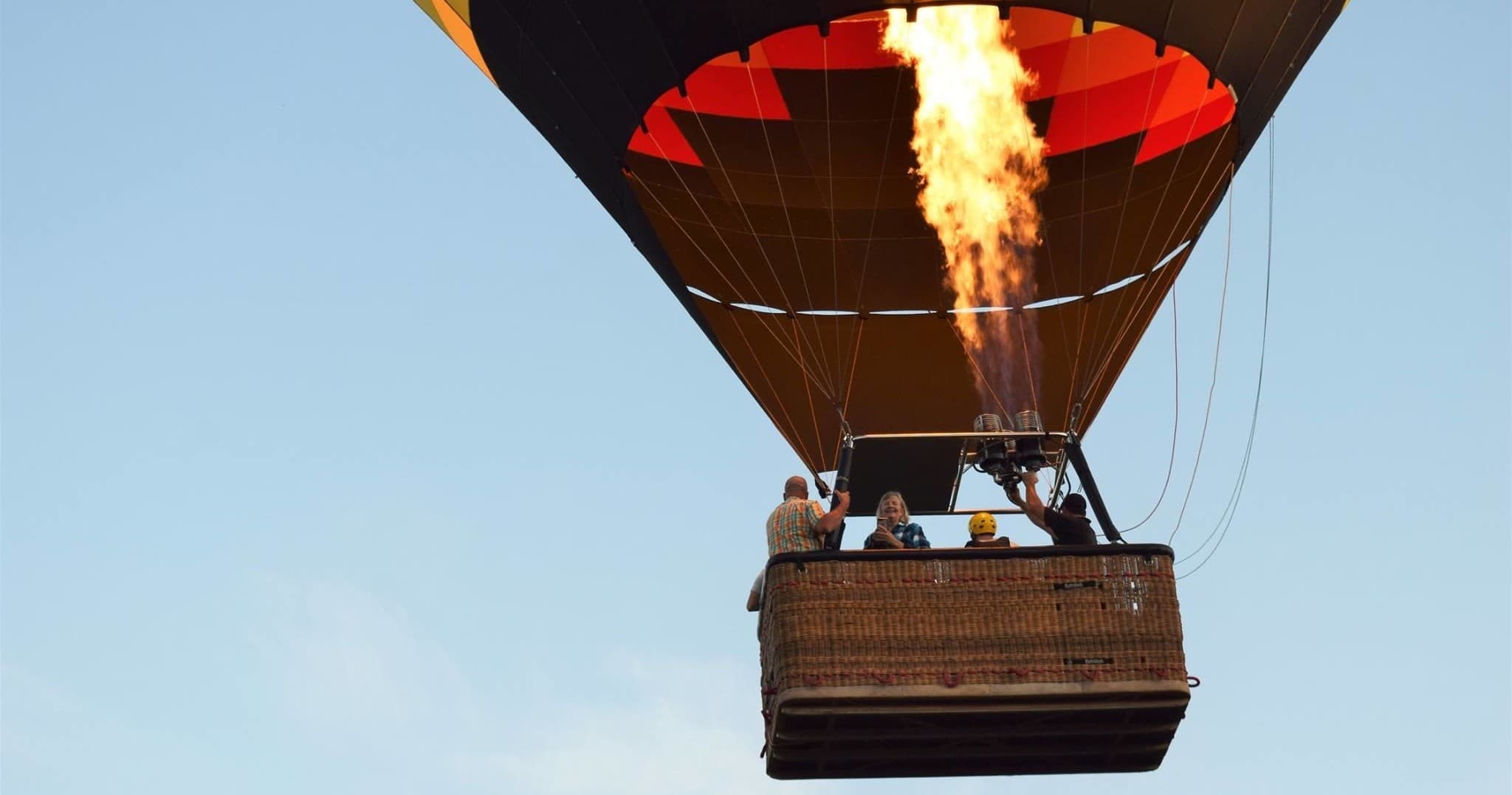 Hot air balloon basket with burner flame ascending in sky