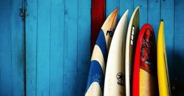 Colorful surfboards leaning against blue beach shack wall