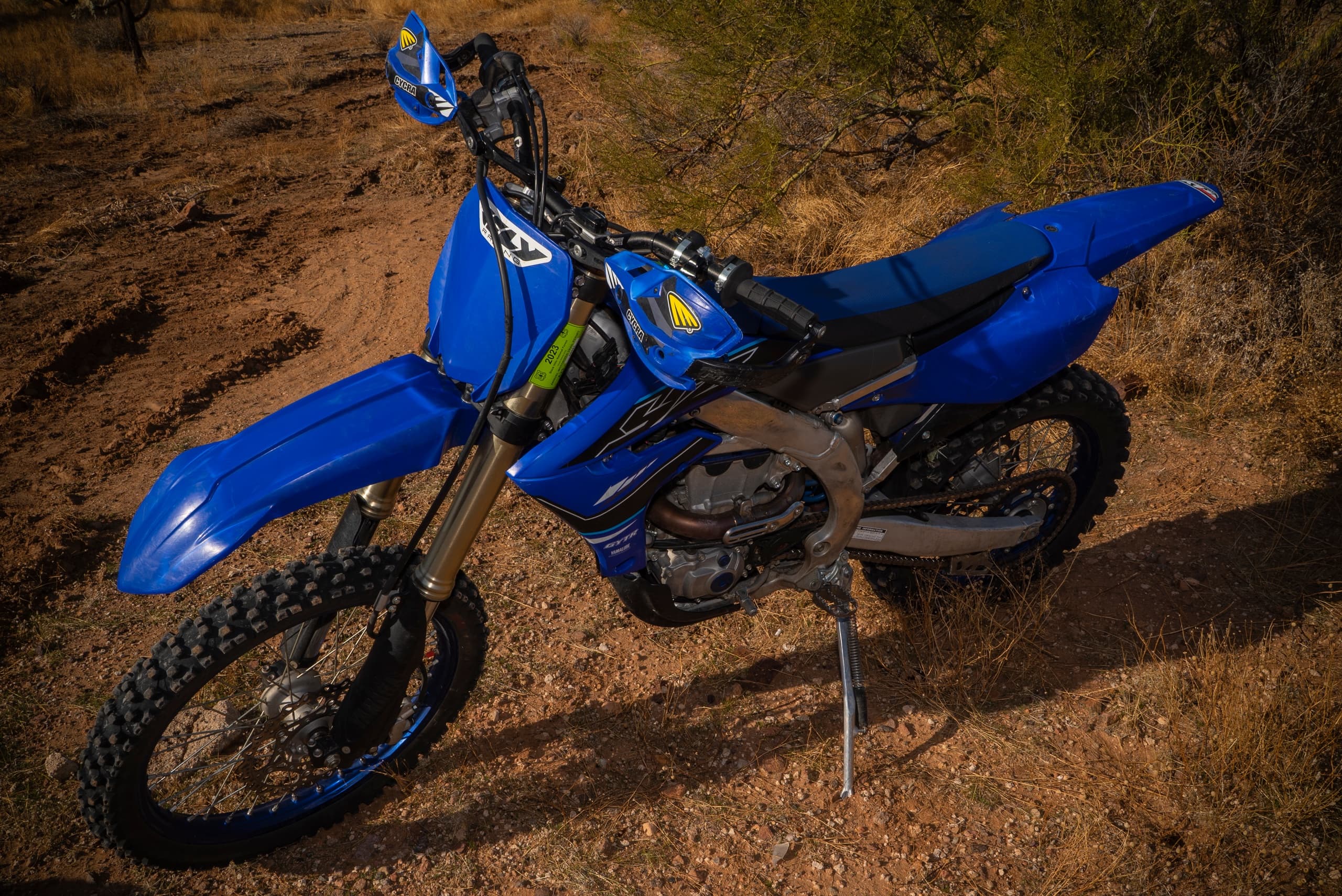 Blue dirt bike resting on arid off-road trail in desert