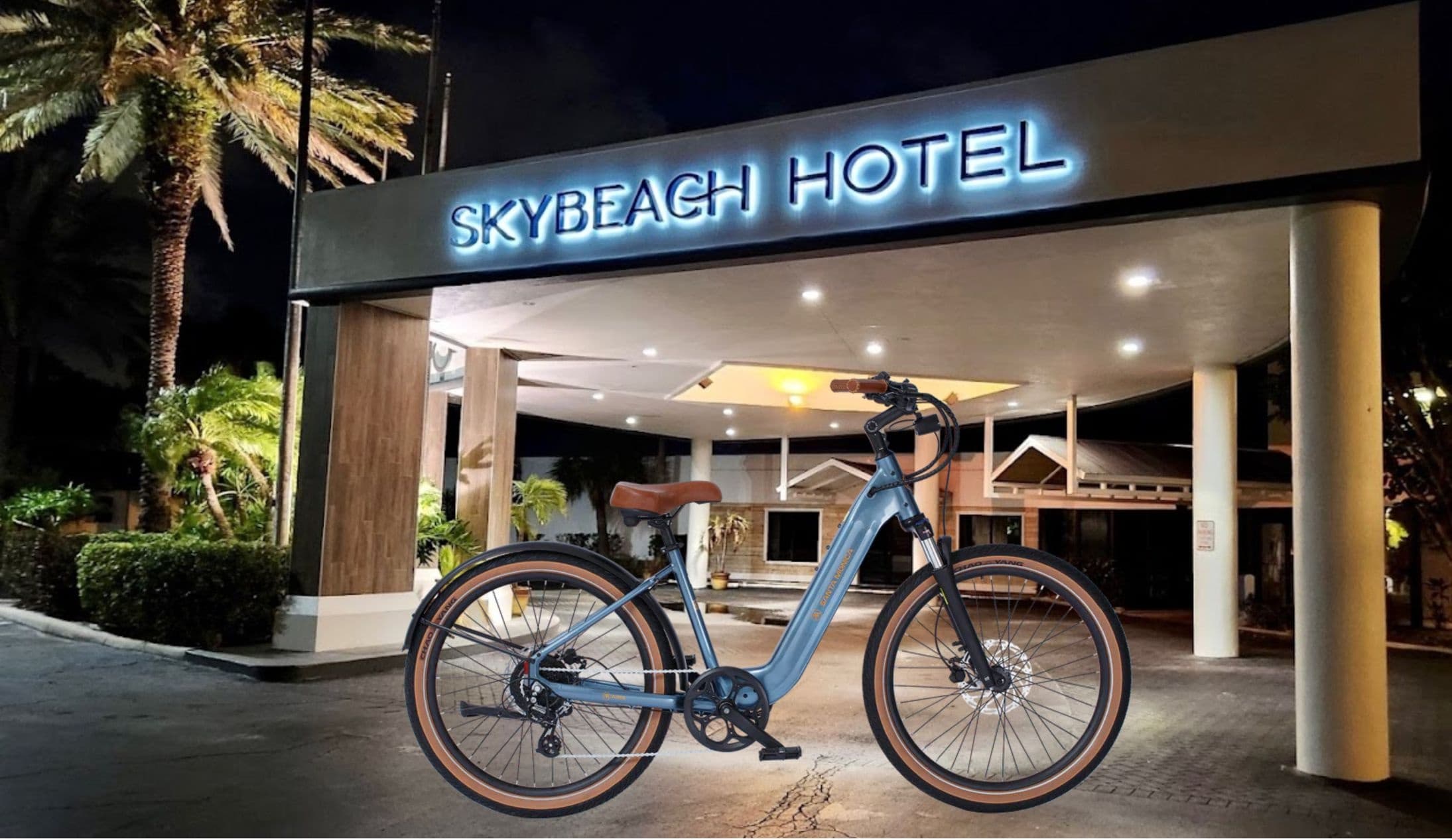 Electric bike parked at hotel entrance with palm trees at night