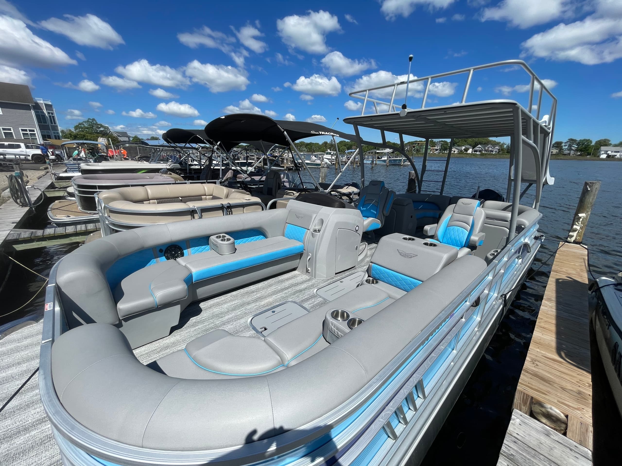 Blue-gray pontoon boat with lounge seating moored at dock