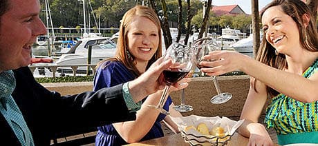 Friends toasting wine on marina deck enjoying waterfront dining