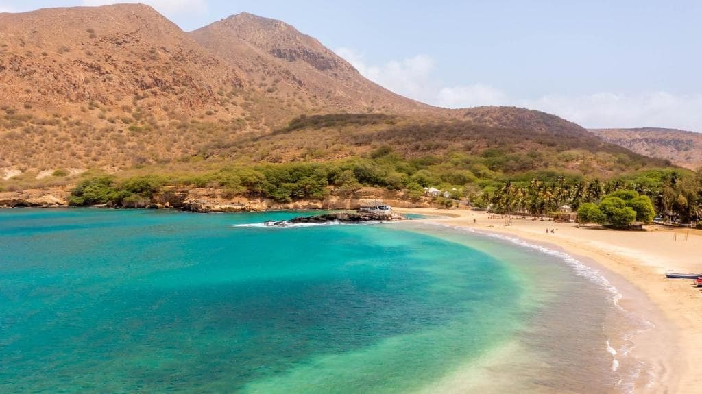 Secluded turquoise cove framed by rugged hills and sandy beach
