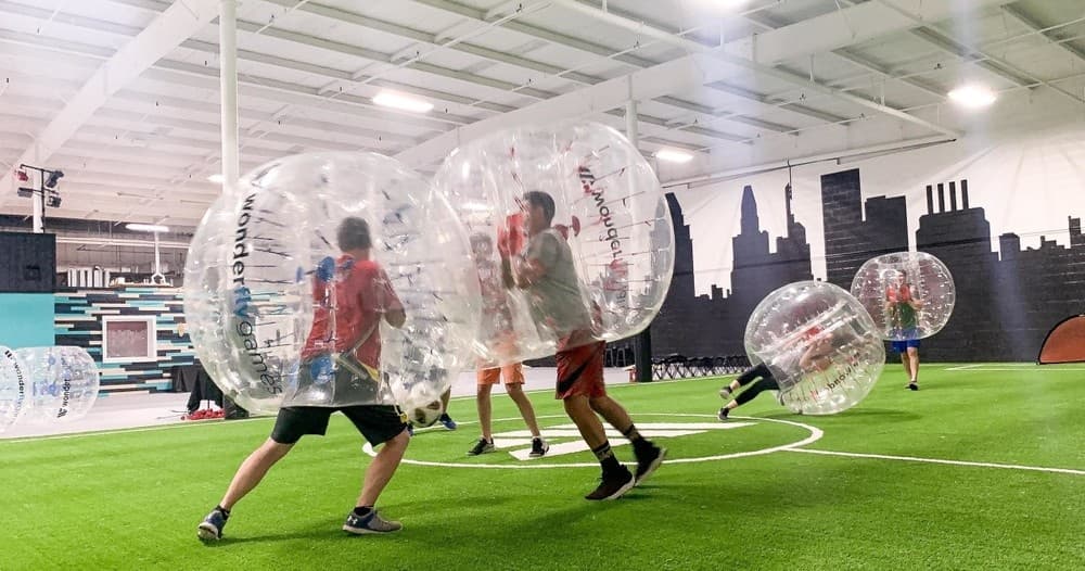 Players bubble soccer on indoor turf arena during match