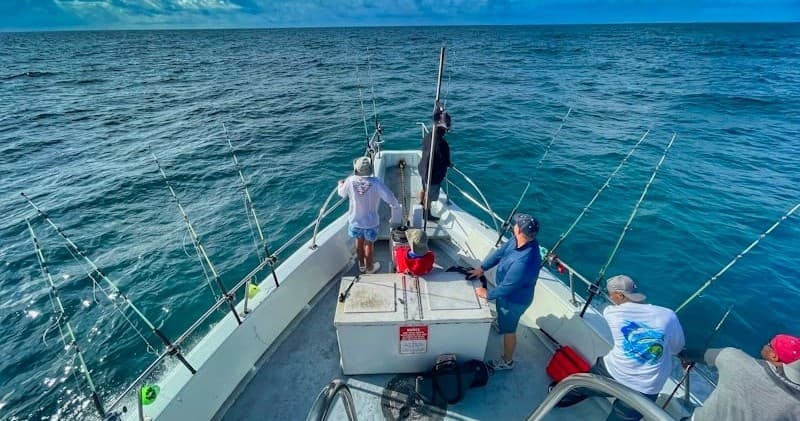 Charter fishing trip on ocean boat with anglers battling fish