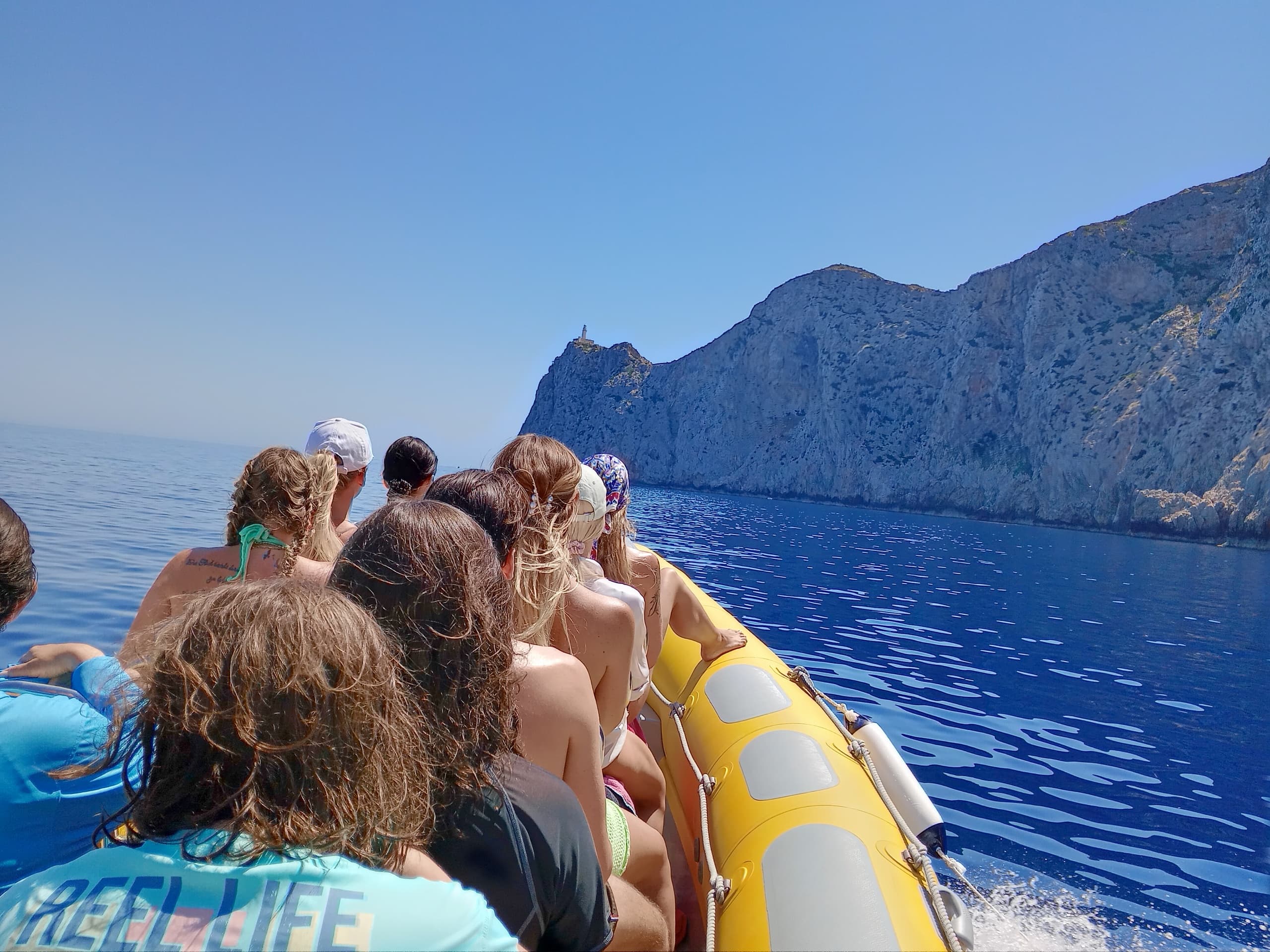 Passengers on inflatable boat approaching coastal cliffs