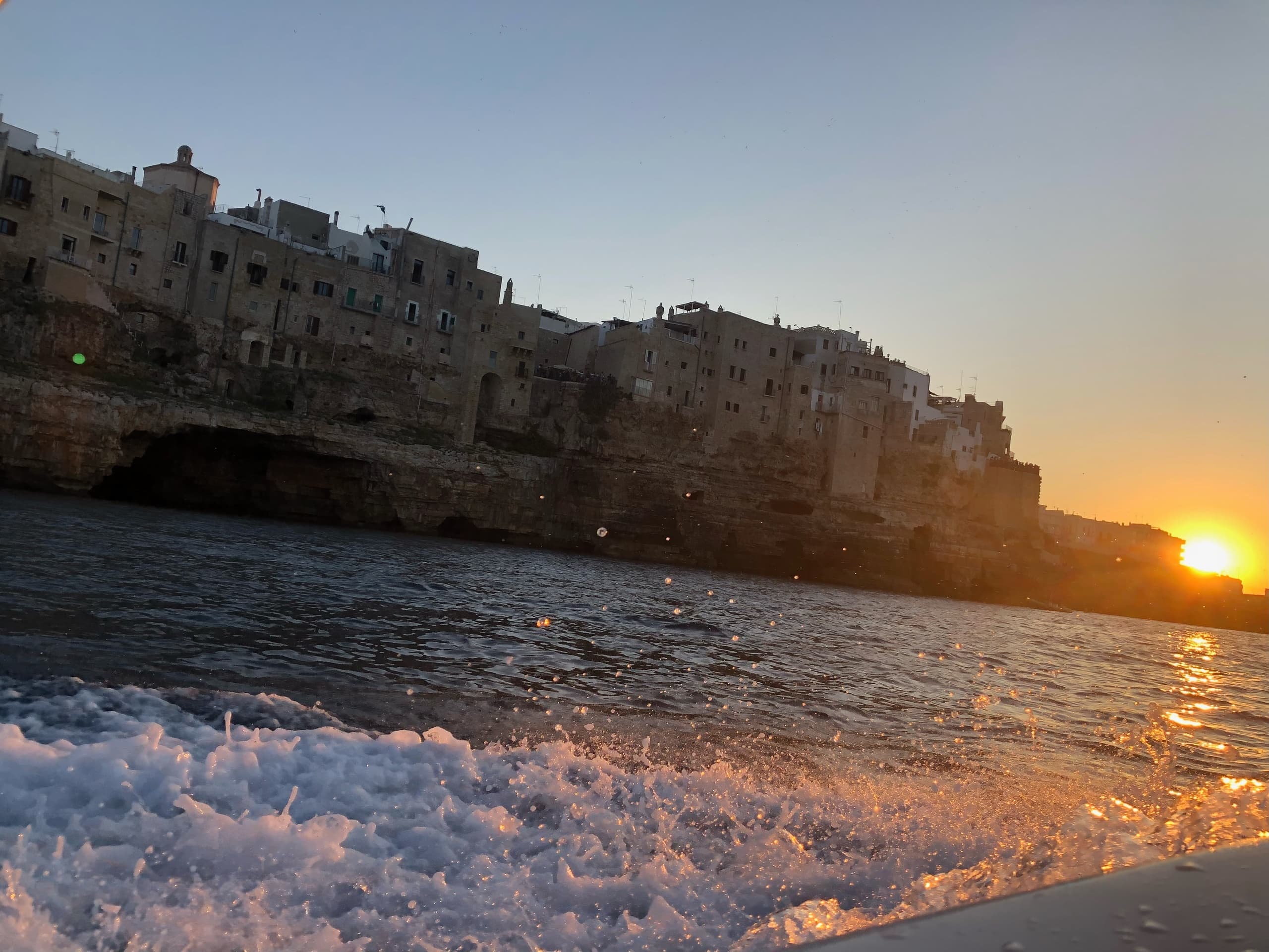 Coastal sunset with sea spray and historic cliffside village view