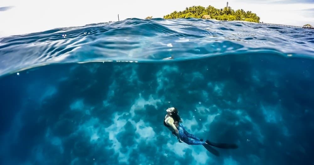 Over-under snorkeler and tropical islet, reef exploration