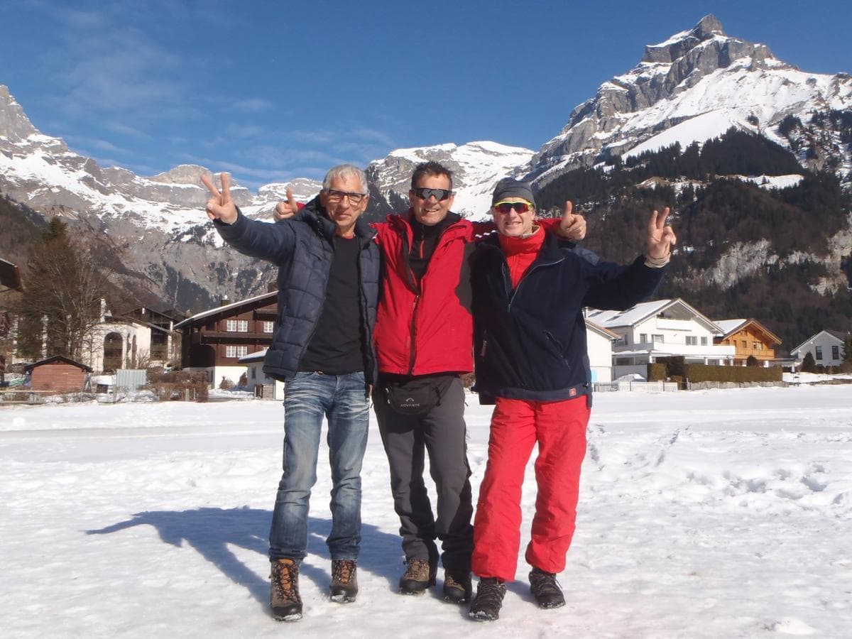 Friends posing on snowy alpine meadow with mountain backdrop