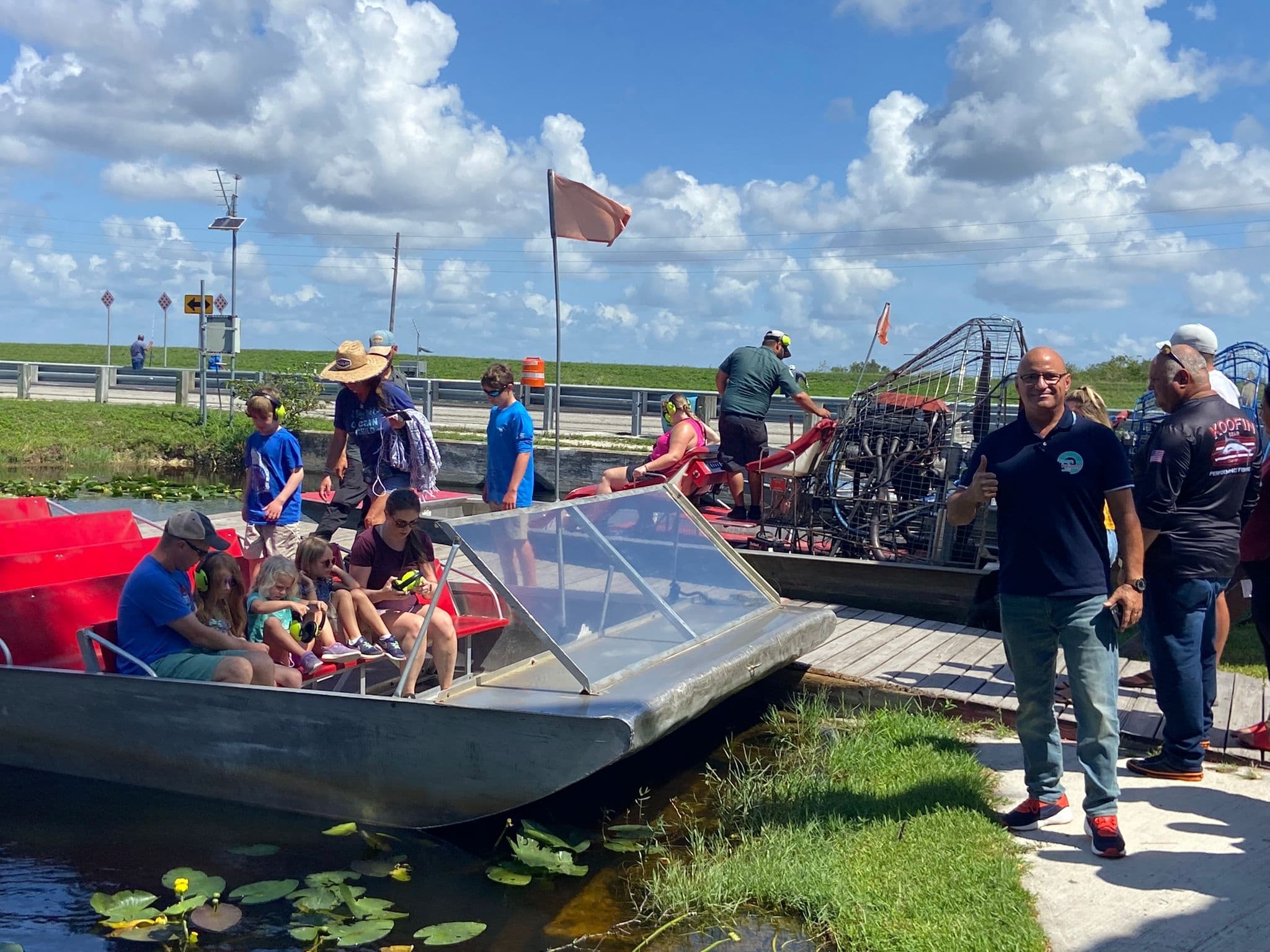 Airboat tour with passengers in grassy marsh, sunny Florida
