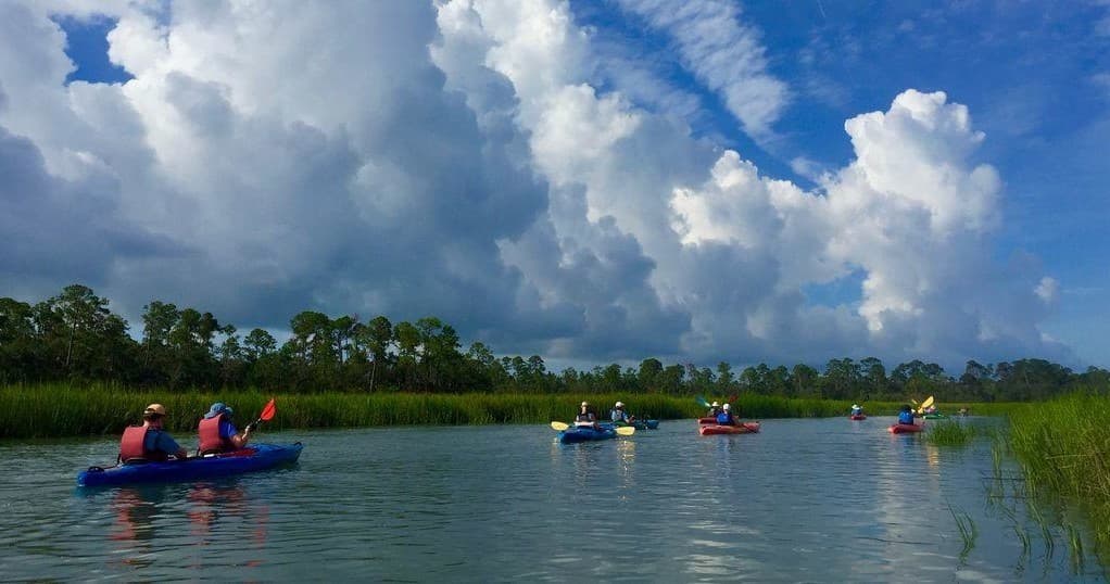 Guided kayak tour through coastal marshes beneath dramatic clouds