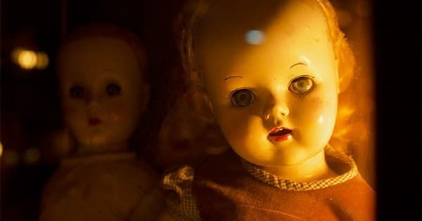 Eerie antique dolls in dim haunted house display, close-up