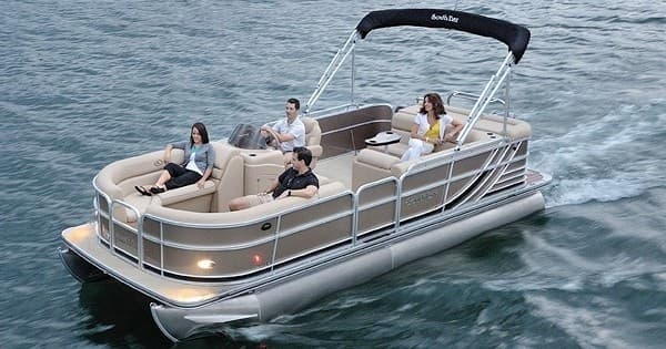 Family pontoon boat on lake sailing across calm blue water