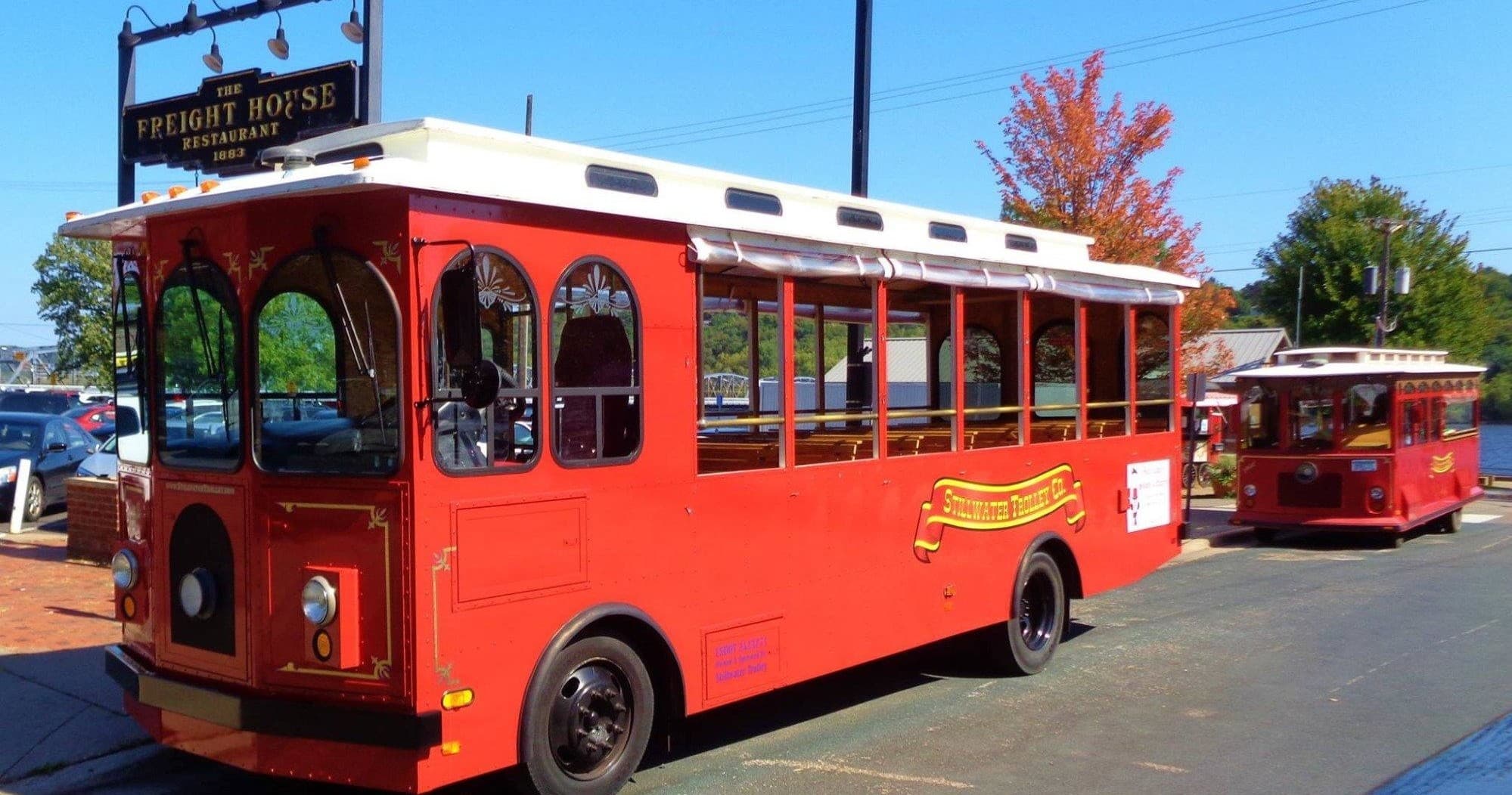 Red sightseeing trolley on sunny street, guided city tour vehicle