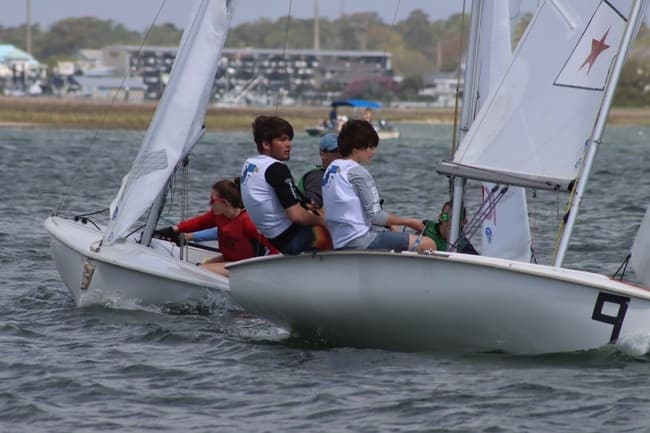 Two-person dinghies racing close-hauled in bay regatta