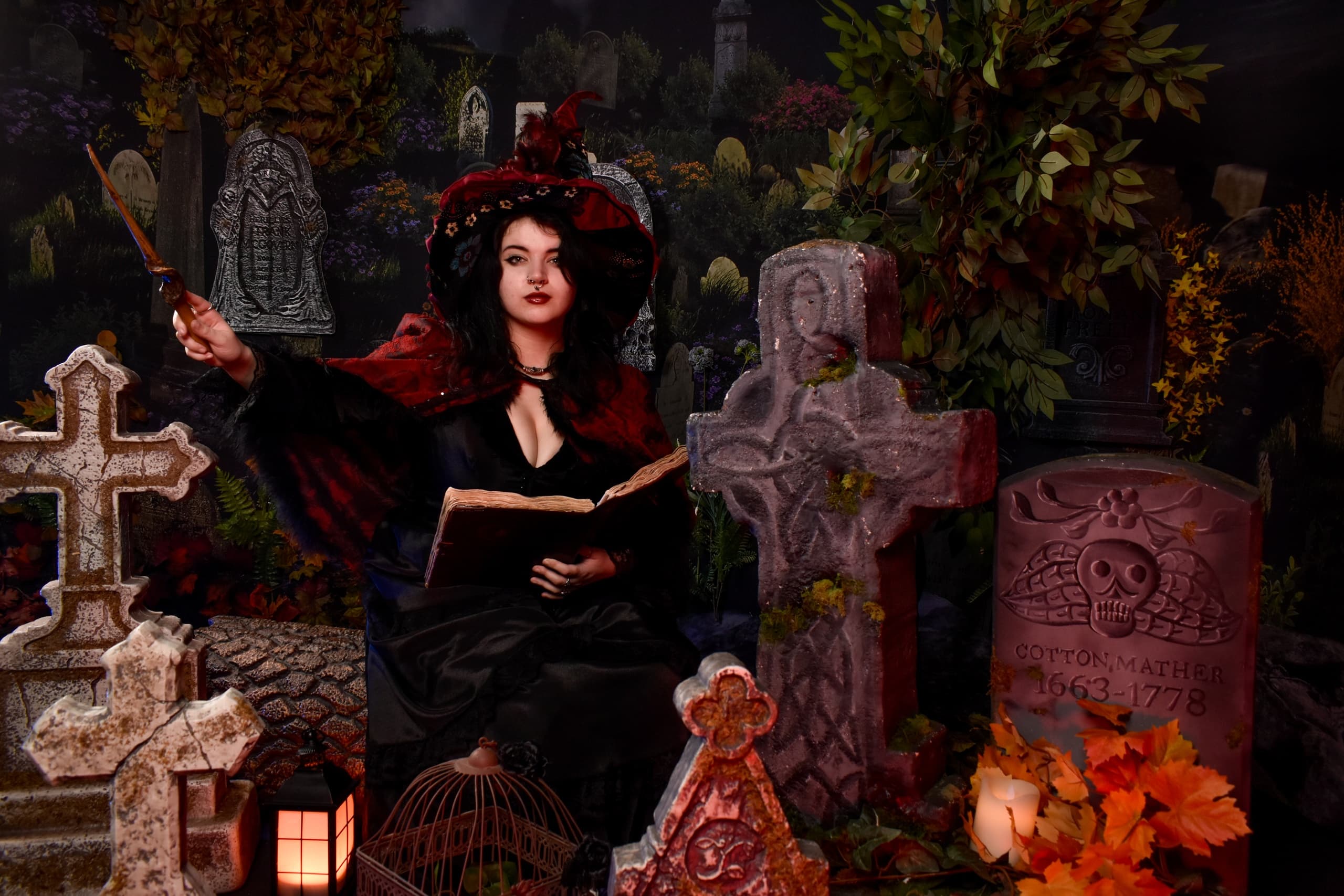 Witch reading spellbook among tombstones in spooky cemetery