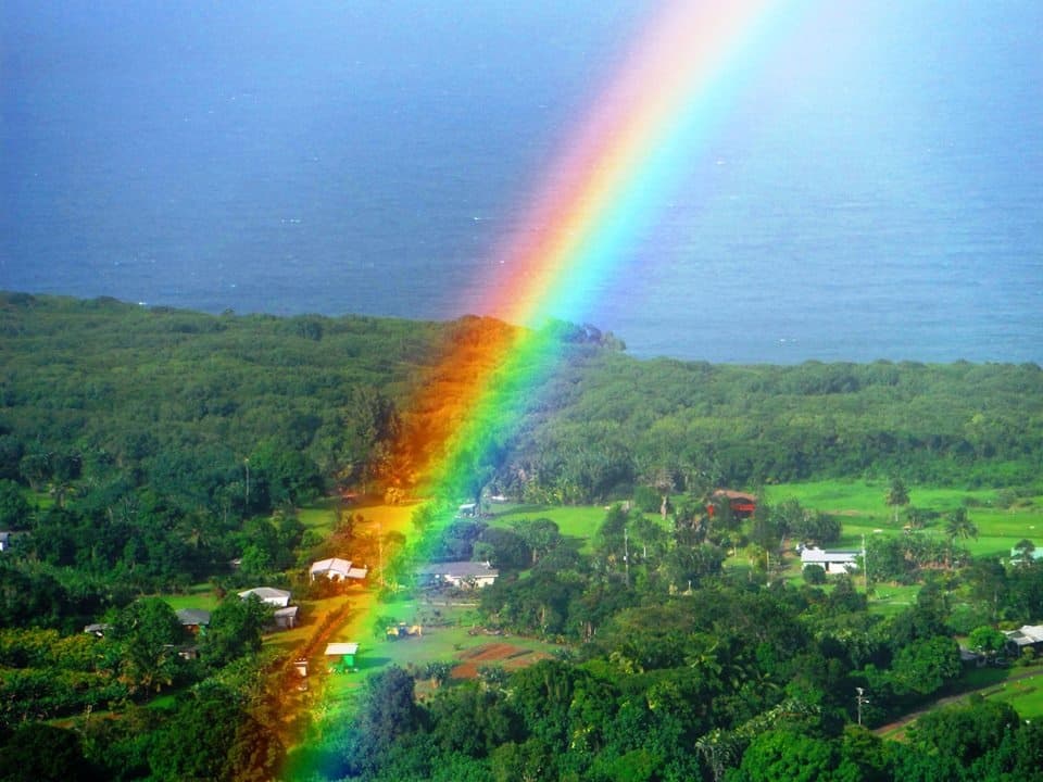Vibrant rainbow arcing over lush valley and coastal town Maui