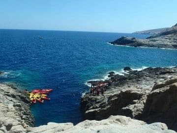 Rocky coastal cliffs with kayaks in clear blue sea
