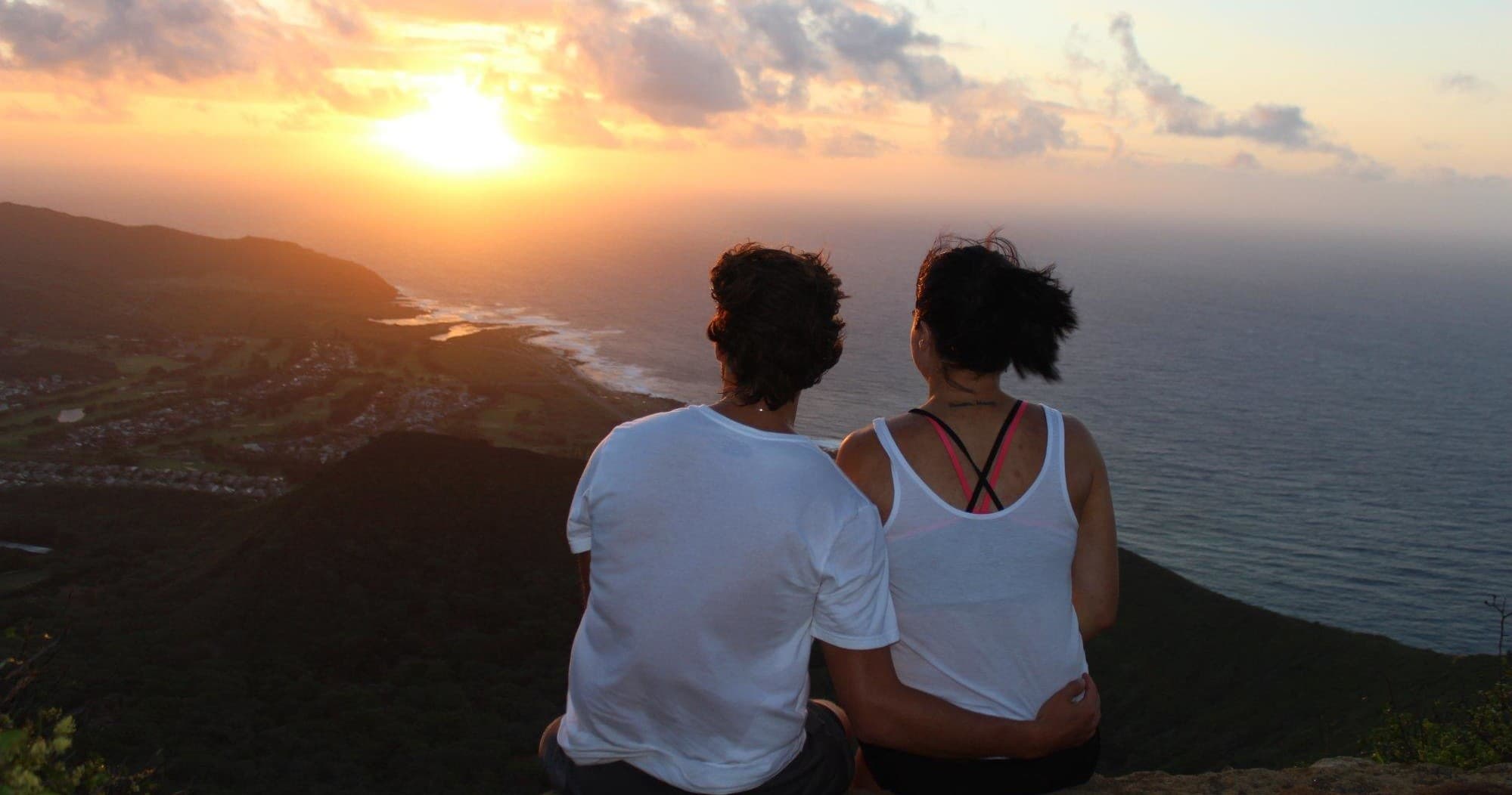 Couple watching sunset over ocean vista on Hawaiian ridge overlook