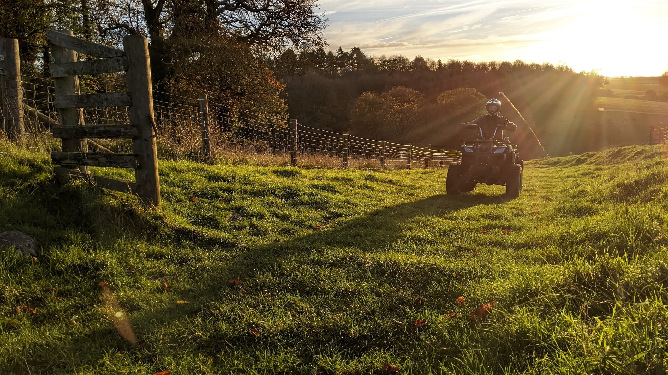 Sunset quad tour silhouette over grassy field creating dramatic view