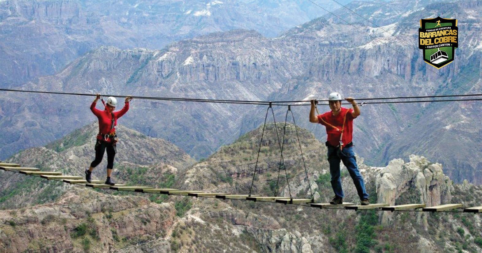 Adventurers crossing suspended rope bridge over canyon in Barrancas