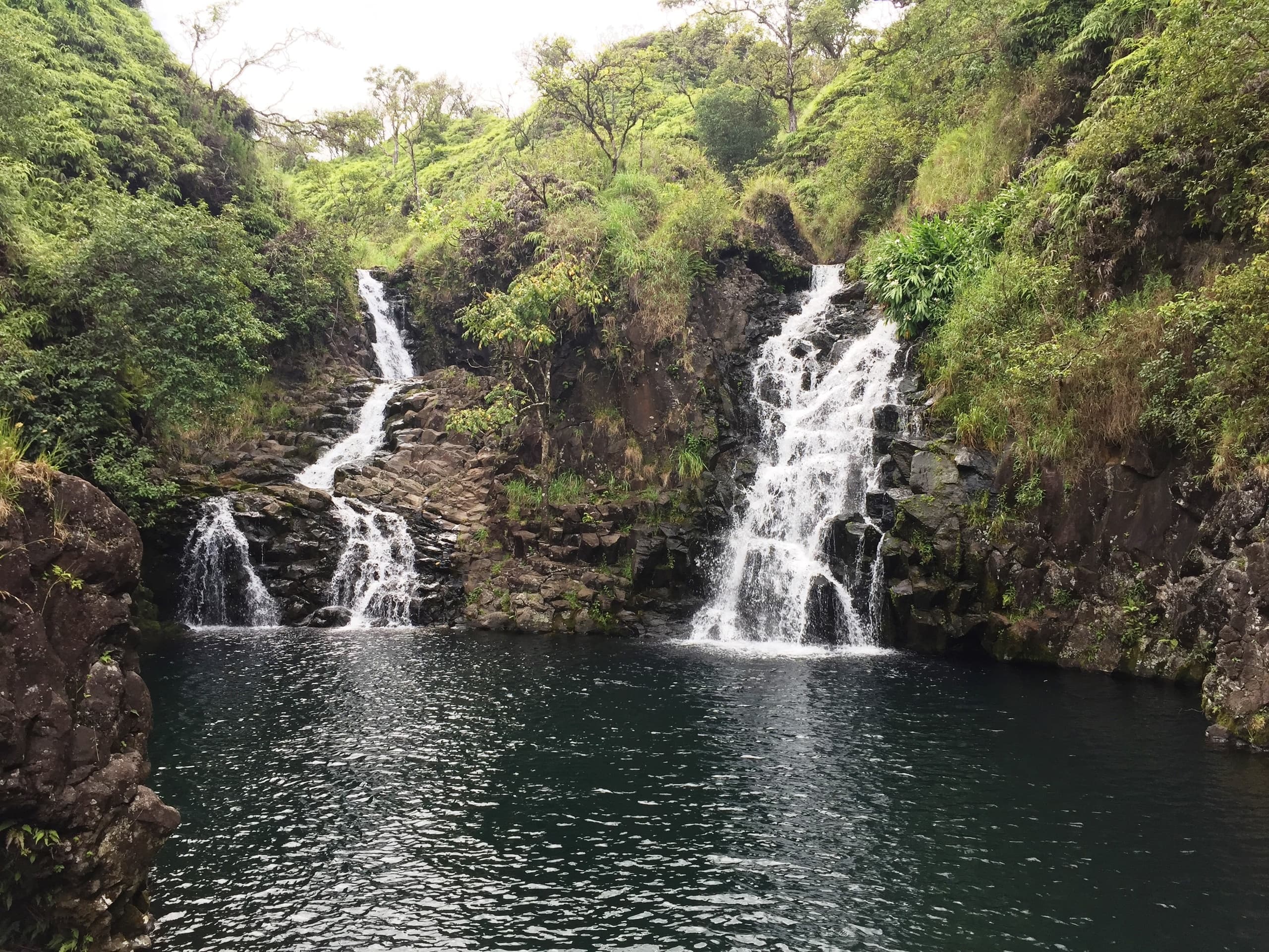 Twin waterfall cascades into emerald pool at tropical gorge