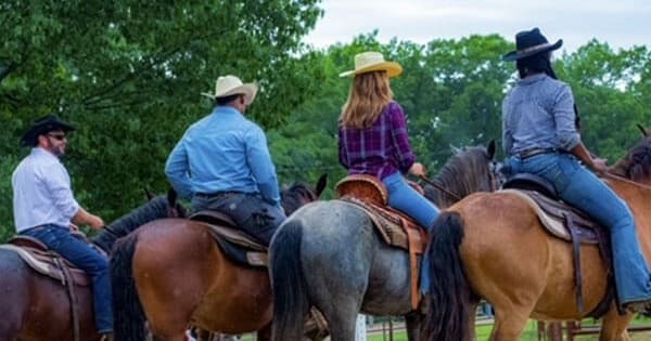 Group horseback riders on a scenic tree-lined ranch trail