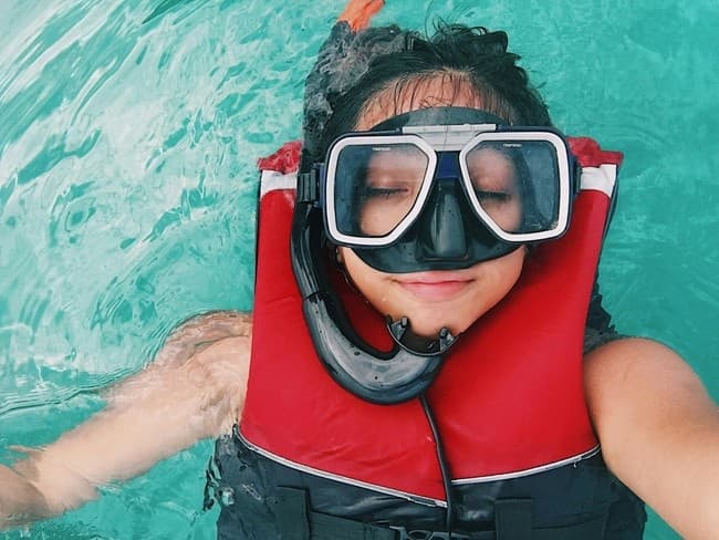 Snorkeler floating with mask and lifejacket in turquoise sea