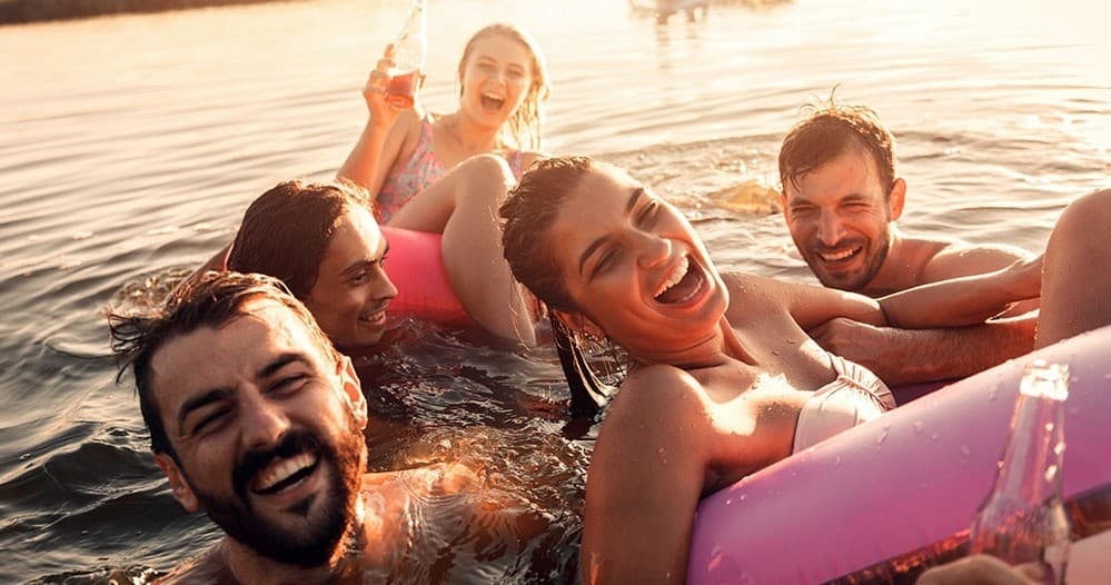 Friends floating on tube in sunlit lake enjoying summer swim