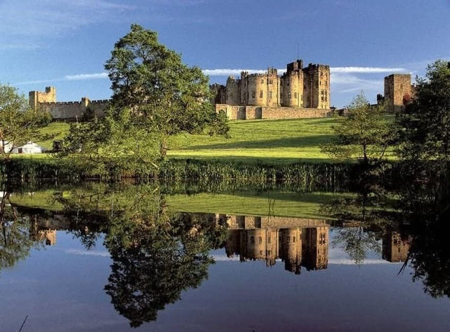 Historic castle reflected on calm Scottish loch at sunset