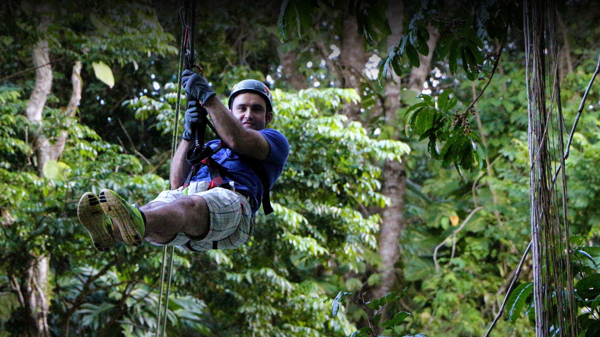 Man ziplining through lush tropical rainforest canopy, Costa Rica