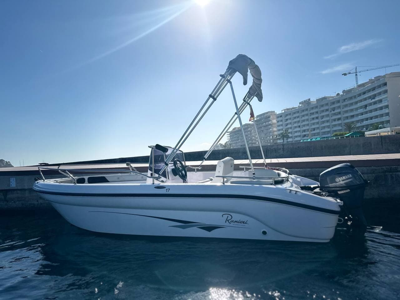 Sunlit white powerboat docked at marina under blue sky