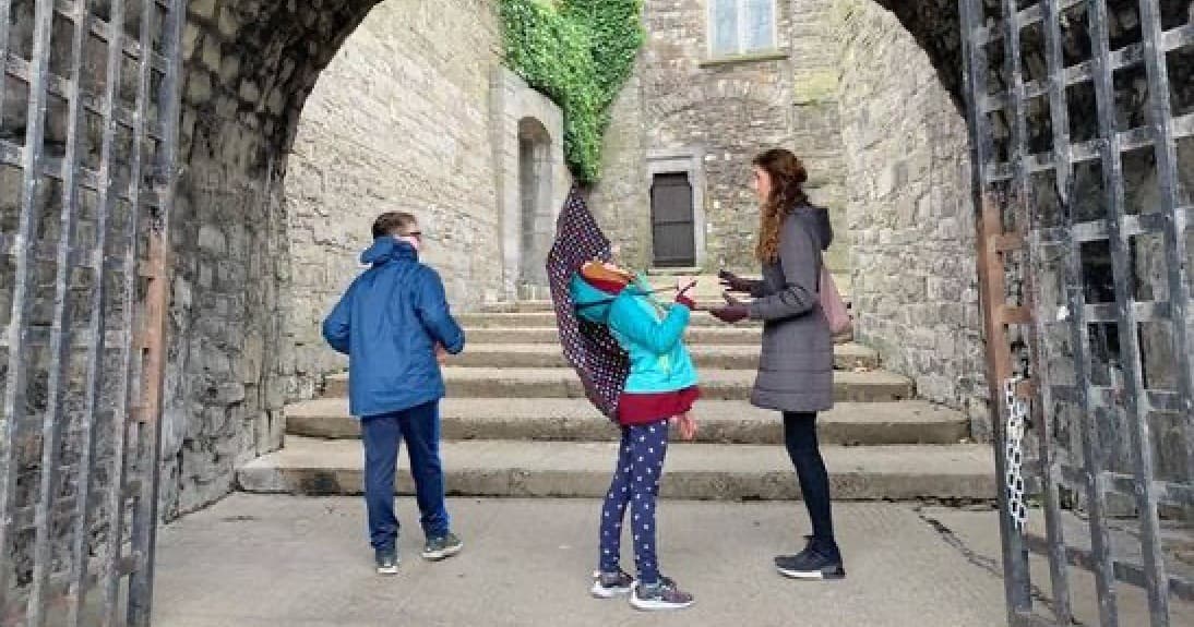 Family guided tour under medieval stone archway at Dublin castle